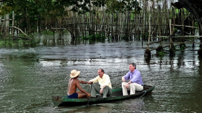 Geraldo Alckmin e Arthur Virgílio tomam uma pequena canoa com um remador nativo para visitar uma casa à beira do rio Paraná do Limão